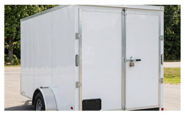 Rear three-quarter view of a secure, white enclosed cargo trailer parked on asphalt in Jacksonville, TX.