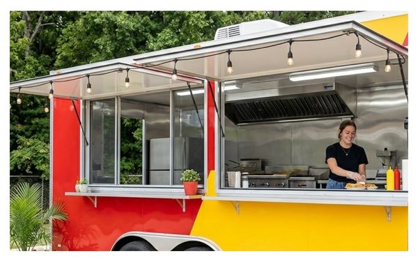 A bright, unbranded custom concession trailer set up for business on a sunny day in Jacksonville, TX, featuring raised service awnings and string lights.